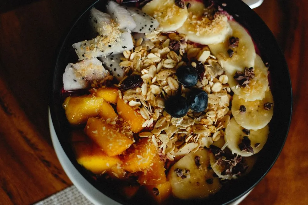 A breakfast bowl topped with fresh fruit and granola