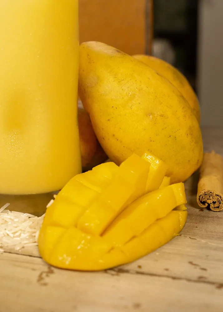 Sliced ripe mango beside a glass of mango juice